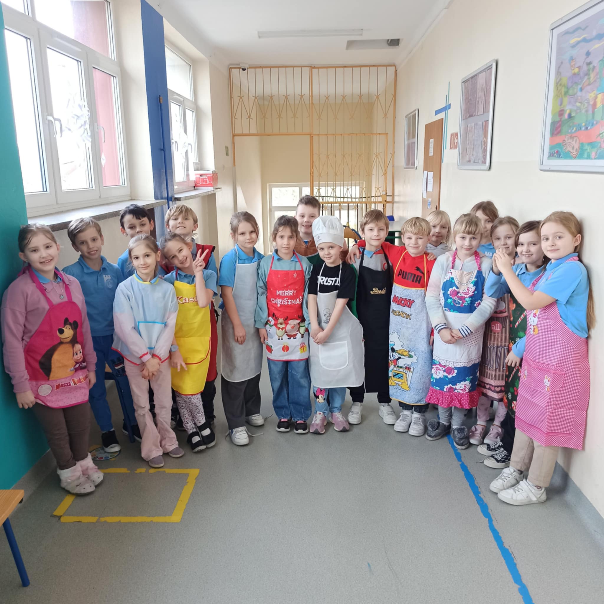 Grupa uczni&oacute;w pozująca do zdjęcia w&nbsp;fartuszkach kucharskich