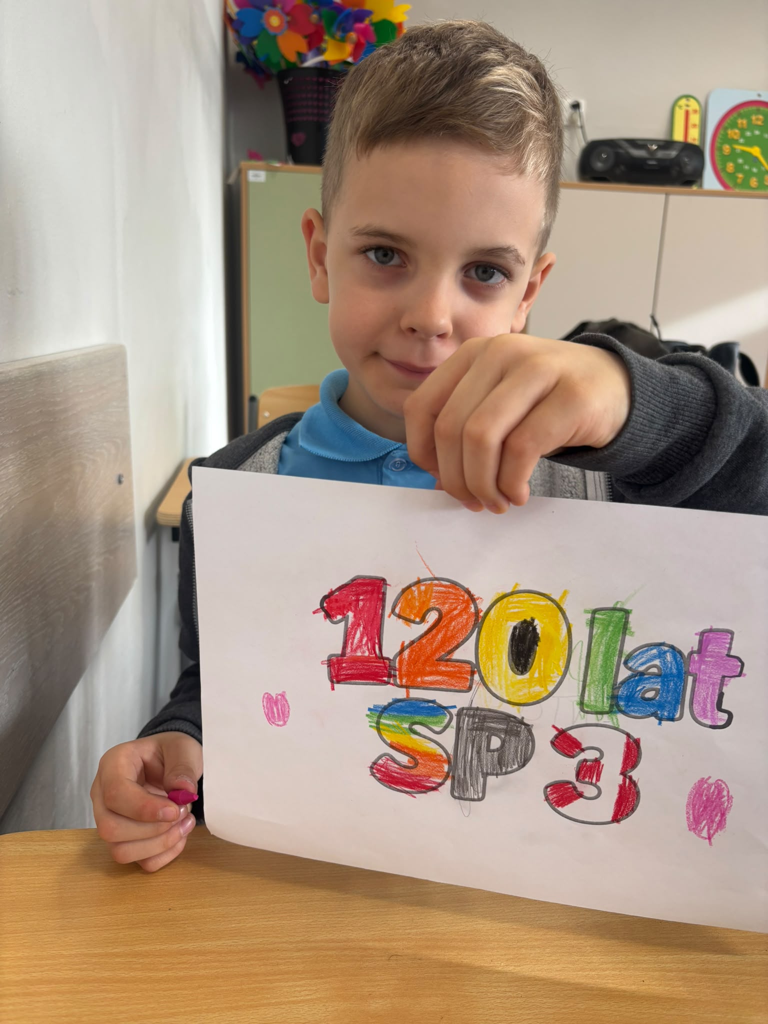 Chłopiec trzymający pokolorowany napis 120 lat SP3